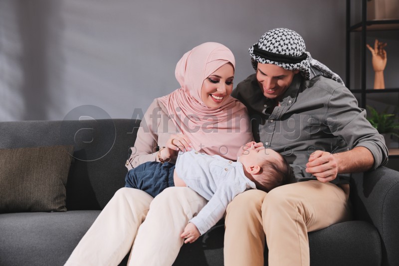 Happy Muslim family with little son in living room