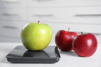 Ripe apples and modern digital scale on table