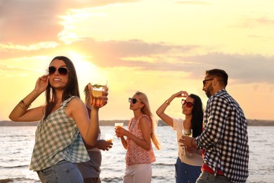 Woman with friends having fun near river at summer party