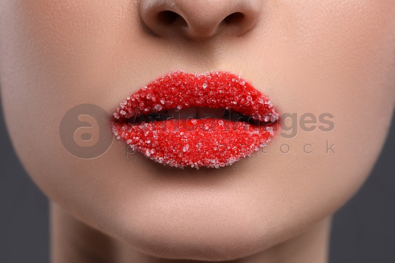 Woman with beautiful lips covered in sugar on grey background, closeup