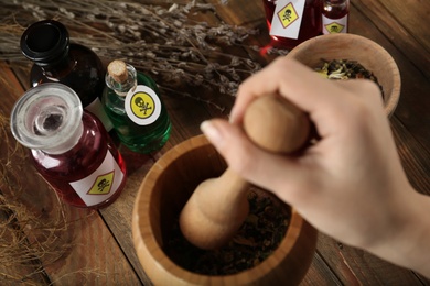 Woman preparing poison at wooden table, closeup
