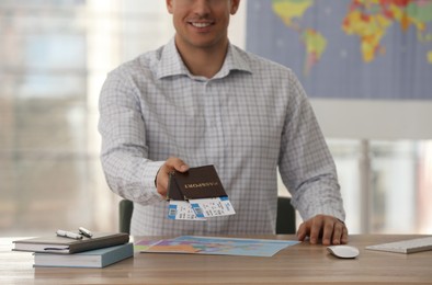 Travel agent with tickets and passports in office, closeup