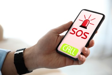 Man holding smartphone with emergency call SOS on screen indoors, closeup