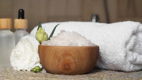 Bowl with bath salt and cosmetic product near fluffy towel on wicker mat indoors