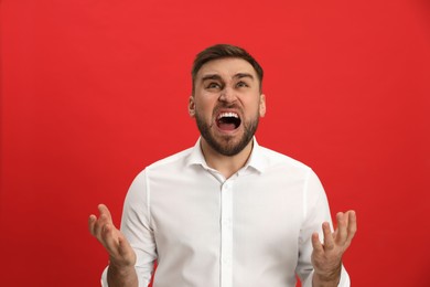 Angry young man on red background. Hate concept