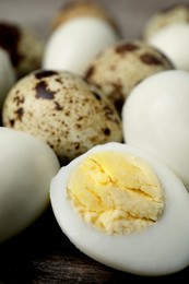Photo of Peeled and unpeeled hard boiled quail eggs on wooden table, closeup