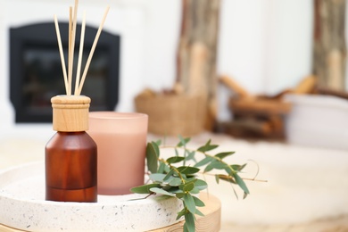 Reed air freshener with candle and eucalyptus branches on tray indoors, closeup