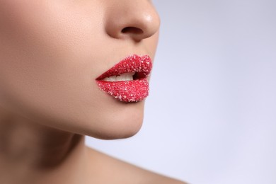Young woman with lips covered in sugar on light background, closeup. Space for text
