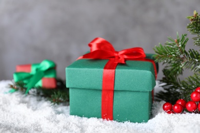 Christmas gift box on artificial snow against grey background, closeup