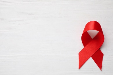 Top view of red ribbon on white wooden background, space for text. AIDS disease awareness