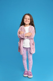 Full length portrait of cute little girl on light blue background
