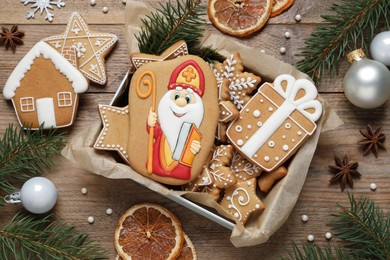 Tasty gingerbread cookies and festive decor on wooden table, flat lay. St. Nicholas Day celebration