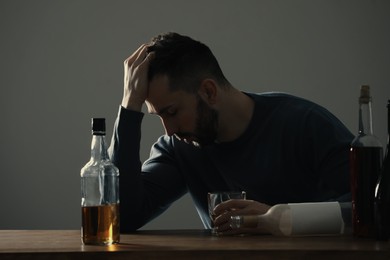 Addicted man with alcohol drink at wooden table indoors