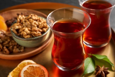 Tray with glasses of traditional Turkish tea, walnuts, dried orange and anise, closeup