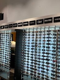 Photo of Poland, Warsaw - July 12, 2022: Many stylish sunglasses from popular brands on racks in shopping mall