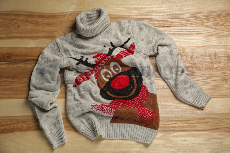 Photo of Warm Christmas sweater on wooden table, top view