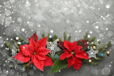 Flat lay composition with traditional Christmas poinsettia flowers and space for text on grey table. Snowfall effect