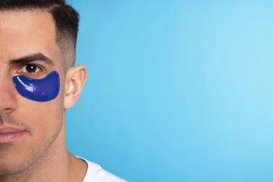 Man with under eye patch on light blue background. Space for text