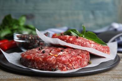 Raw meat cutlets for burger on wooden table, closeup