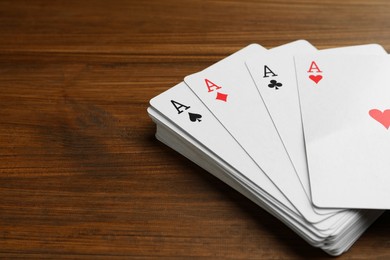 Photo of Four aces playing cards on wooden table, closeup. Space for text