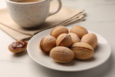 Photo of Homemade walnut shaped cookies with boiled condensed milk on white marble table, closeup
