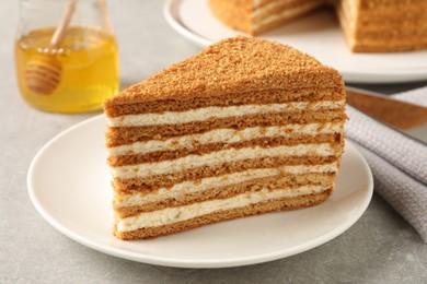 Slice of delicious layered honey cake served on grey table, closeup