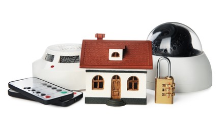 Photo of House model, CCTV camera, remote controls, lock and smoke detector on white background. Home security system