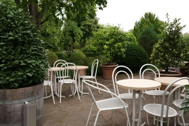 Photo of Beautiful garden with tables, chairs and green plants