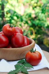 Bowl and fresh tomatoes on wooden table outdoors