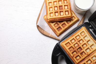 Flat lay composition with fresh Belgian waffles on white wooden table. Space for text