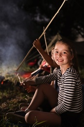 Adorable little girl near bonfire at night. Summer camp