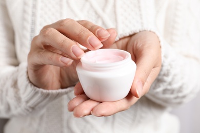 Woman holding jar of moisturizing cream, closeup. Winter skin care cosmetic