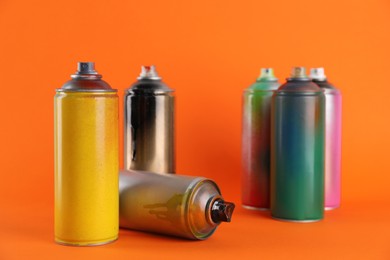 Used cans of spray paints on orange background
