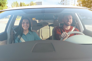 Photo of Young woman and driver in modern car, view through windshield