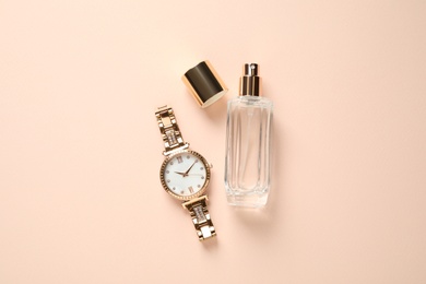 Luxury wrist watch and perfume on beige background, flat lay