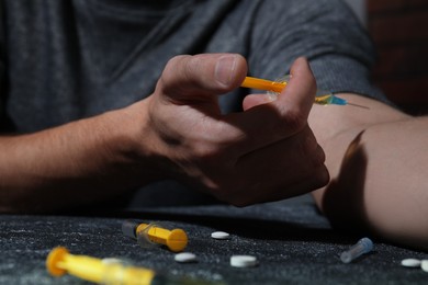 Photo of Addicted man taking drugs at black textured table, closeup