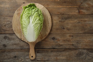 Photo of Cutting board with fresh ripe Chinese cabbage on wooden table, top view. Space for text