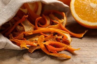 Photo of Dry orange peels and fresh fruit on wooden table, closeup
