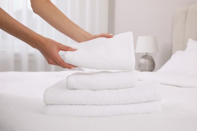 Chambermaid putting fresh towels on bed in hotel room, closeup