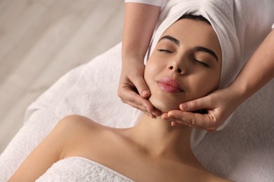 Photo of Beautiful woman receiving facial massage in beauty salon, closeup