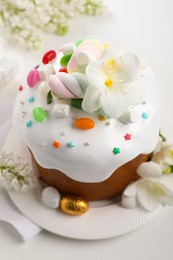 Photo of Traditional Easter cake with sprinkles, jelly beans, marshmallows and decorated eggs on white table, closeup