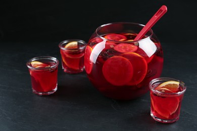 Glasses and bowl of delicious aromatic punch drink on black table