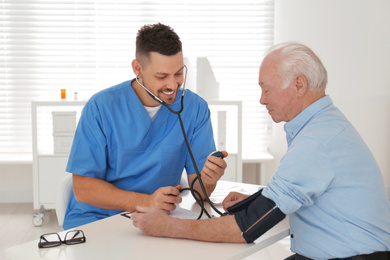 Doctor measuring blood pressure of senior patient in office