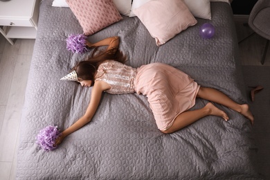 Exhausted woman in festive outfit sleeping on bed at home after party, above view