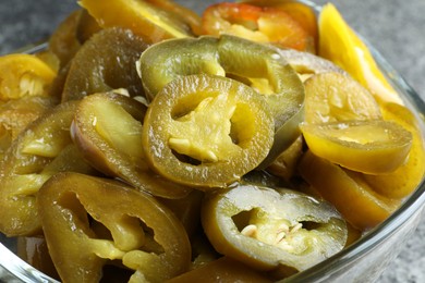 Photo of Glass bowl with slices of pickled green jalapeno peppers, closeup