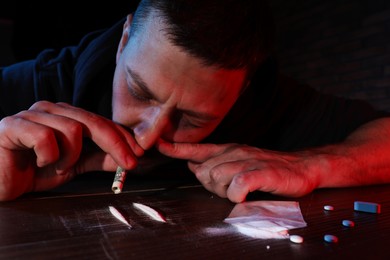 Drug addicted man taking cocaine at table