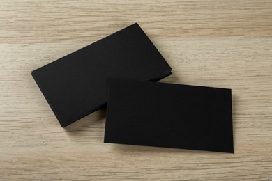 Blank black business cards on wooden background, above view. Mockup for design