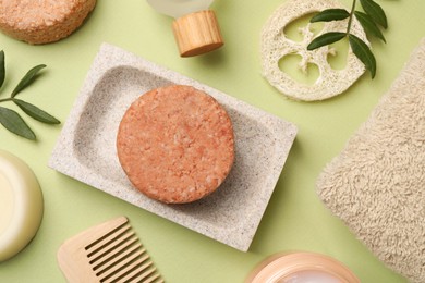 Flat lay composition of solid shampoo bars, loofah and comb on green background. Hair care