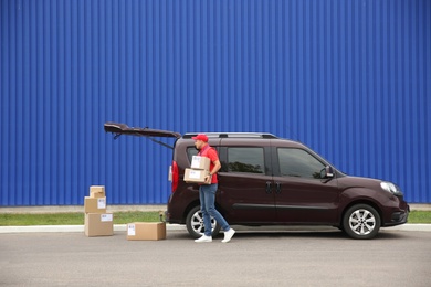 Courier loading packages in car outdoors, space for text