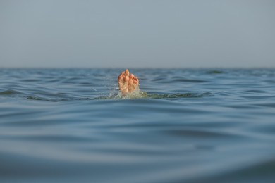 Drowning woman's feet sticking out of sea